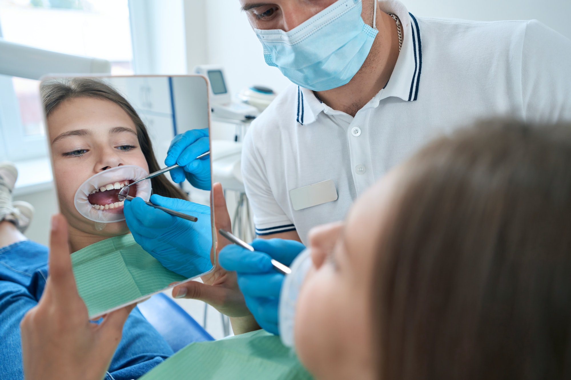Pediatric dentist performing dental examination of teenage patient