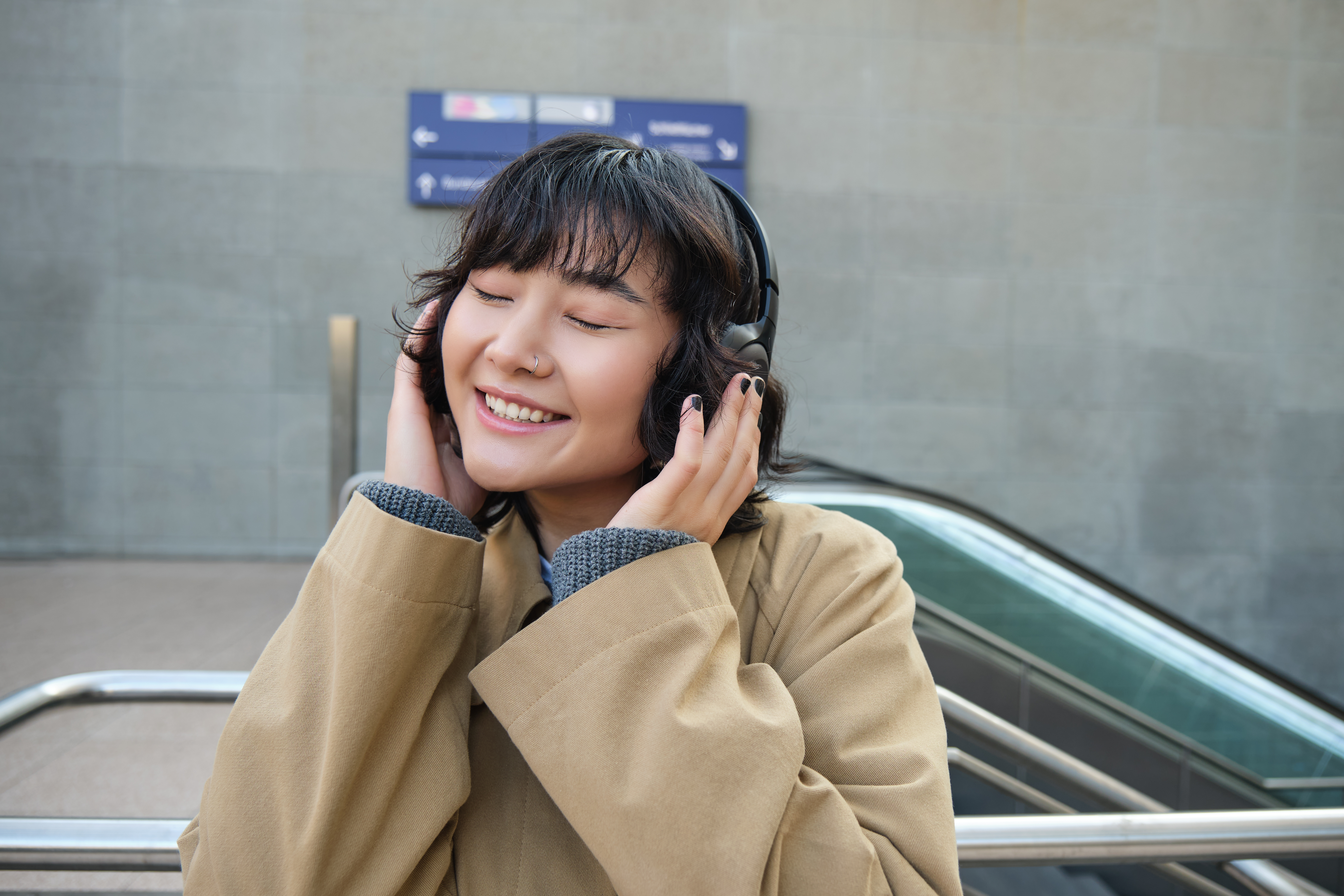 Portrait of happy woman, korean girl in headphones, listening music in headphones, enjoying sound
